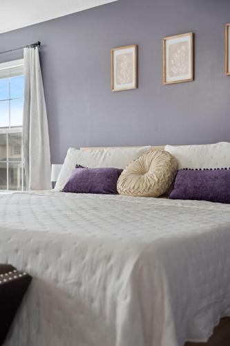a large white bed with purple pillows and a window at Spacious King Suite, Game Room, Patio, Firepit in Lexington