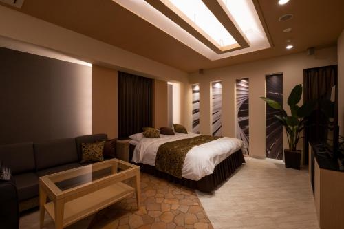 a bedroom with a bed and a couch and a skylight at HOTEL MYTH-U -Adult only in Wakayama