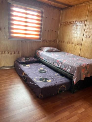 two beds in a room with a window at Villa Lagunitas in Puerto Montt