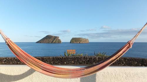 a hammock in front of the ocean with two islands at Casa Beira Mar in Angra do Heroísmo