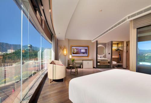 a hotel room with a bed and a large window at Orange Crystal Hotel Dali Erhai Park in Dali