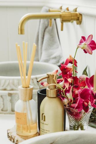 Ein Waschtisch im Badezimmer mit zwei Flaschen und einer Blumenvase in der Unterkunft Studio 34 - Nelson Bay in Nelson Bay
