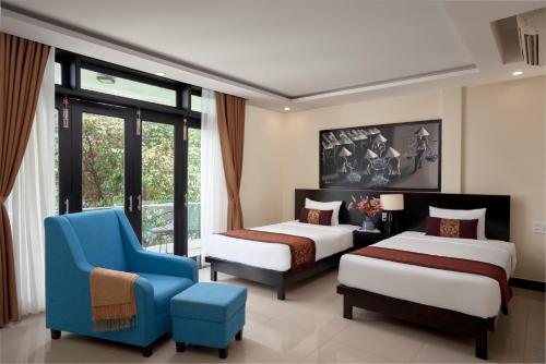 a hotel room with two beds and a blue chair at Banana Garden Hoi An in Hoi An