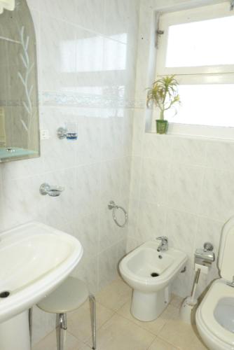 a white bathroom with a sink and a toilet at Room 2 - Music House in Bicas