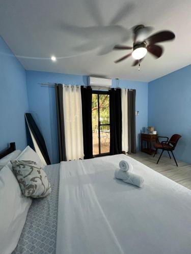 a bedroom with a white bed with a ceiling fan at Magalong Beach Resort in Busuanga