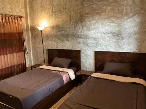 a bedroom with two beds and a lamp at Rai Phuchat in Ban Pa Thon