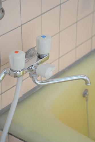 a bathroom with a bath tub with two cups at 地獄の三丁目 鬼のすみか in Beppu