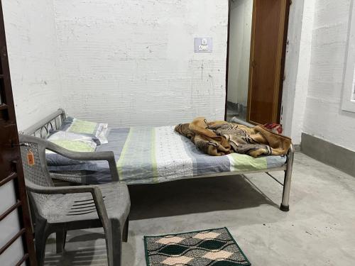 a bed in a room next to a chair at Pushpa Nilayam in Khaprail