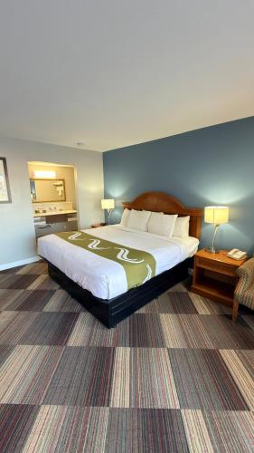 a hotel room with a large bed and a chair at Regency Inn in Chickasha