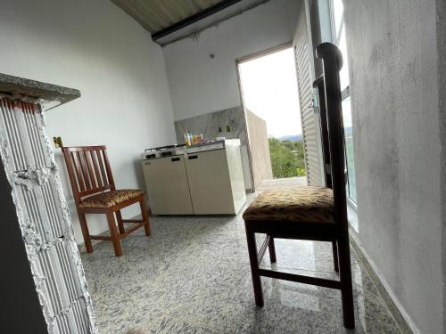 a kitchen with two chairs and a refrigerator and a window at Flat Recanto Brados in Sao Jorge