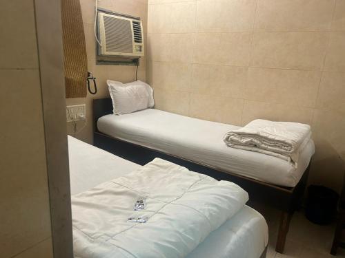 two beds in a small room with white sheets at Hotel Kamal in Mumbai