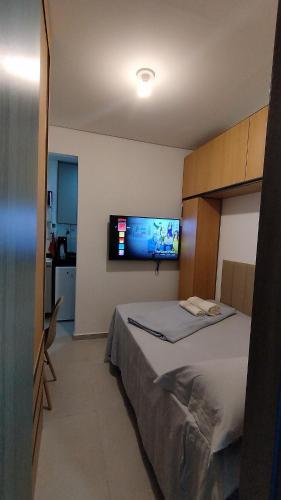 a bedroom with a bed and a flat screen tv at Studio moderno e bem localizado in João Monlevade