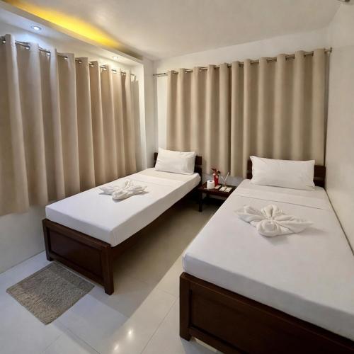 two beds sitting in a room with curtains at Iwayan Beach Resort in Panglao Island