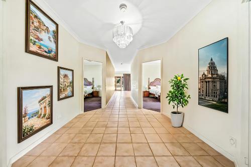 a hallway with paintings on the walls and a potted plant at Cockburn Airoprt 6BR Farmstay nr Fremantle&Beach in Perth