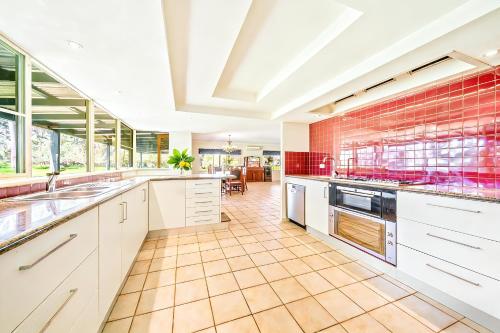 a large kitchen with white cabinets and a brick wall at Cockburn Airoprt 6BR Farmstay nr Fremantle&Beach in Perth