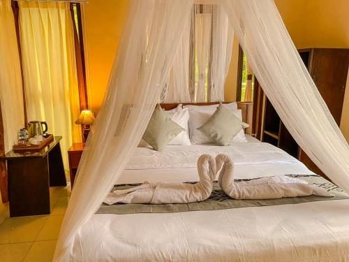 a bedroom with a bed with a mosquito net at Geriya Sena in Munduk