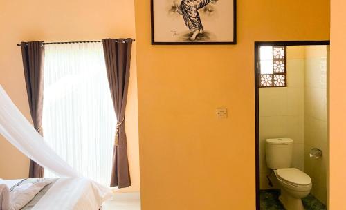 a bathroom with a bed and a toilet and a window at Geriya Sena in Munduk