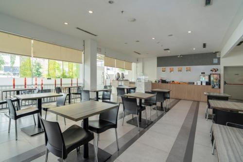 a restaurant with tables and chairs and a kitchen at JP Hotel Pluit Jakarta by LIFE in Jakarta