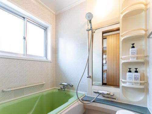 a bathroom with a green tub and a window at 屋島base-最大10名 in Takamatsu