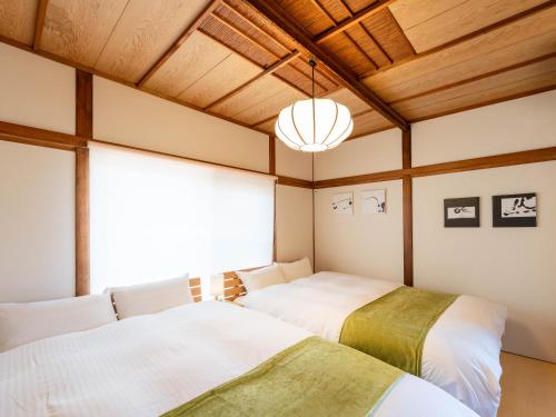 two beds in a room with wooden ceilings at 屋島base-最大10名 in Takamatsu