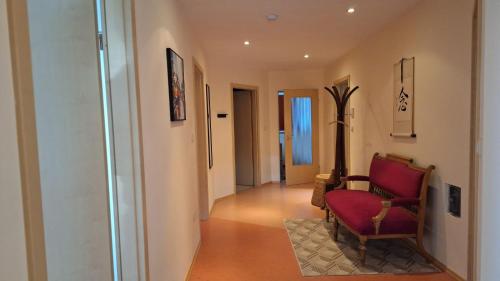 a hallway with a red chair in a room at Sunset Apartment in Grafenwöhr