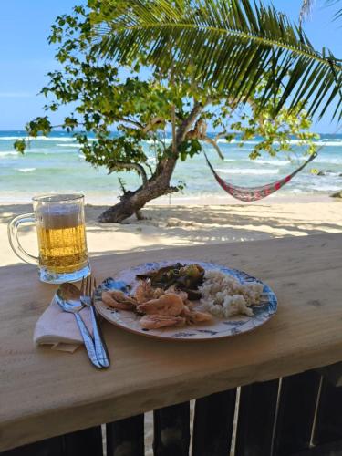 Ein Teller mit Essen auf einem Tisch, dazu ein Glas Bier. in der Unterkunft MORE Beach in El Nido