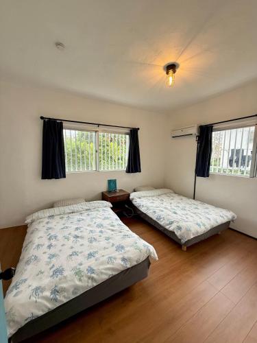 a bedroom with two beds and two windows at P-house Yumearu in Sobe