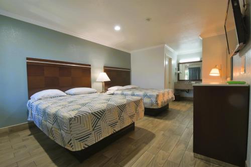 a hotel room with two beds and a flat screen tv at Welcome Inn Corona in Corona