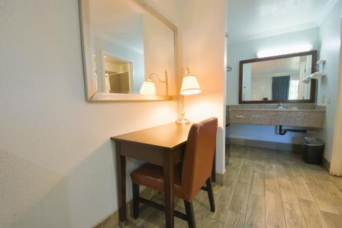 a bathroom with a desk with a mirror and a sink at Welcome Inn Corona in Corona