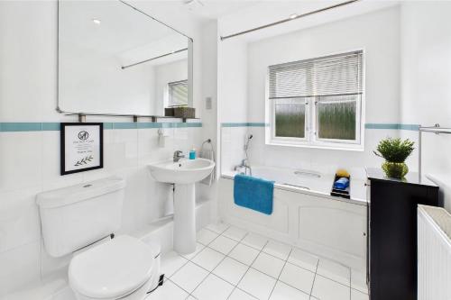 a white bathroom with a toilet and a sink at 2 Ensuite beds house, sleep 4 With free parking, Self Check-in, and Close link to London, Zone 6 in Ewell