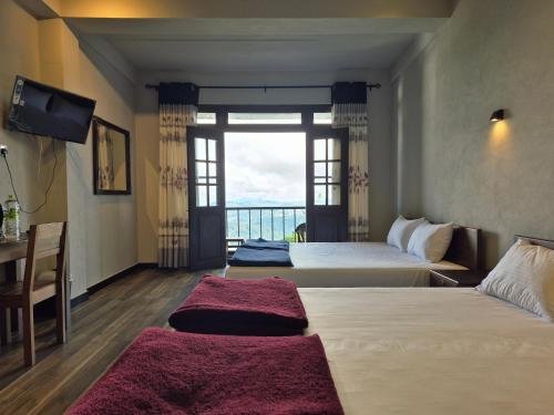 a hotel room with two beds and a balcony at Aroma Holiday Home-Haputhale in Haputale