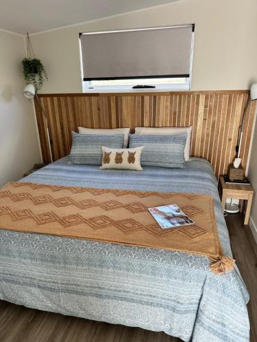 a bedroom with a large bed with a wooden headboard at Badger's View Farmstay Cottage in Railton