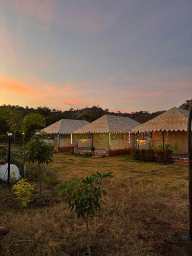 a group of tents in a field at sunset at Aura Resort and Restaurant in Chikalthān