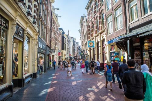 Un groupe de personnes marchant dans une rue avec des bâtiments dans l'établissement The Flying Pig Downtown, à Amsterdam