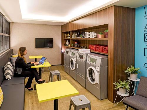 a woman sitting at a table in a laundry room at Mercure Sao Bernardo Do Campo in São Bernardo do Campo