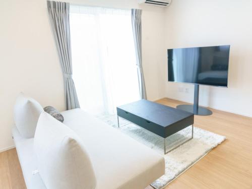 a living room with a white couch and a flat screen tv at Burikina Terrace in Nago