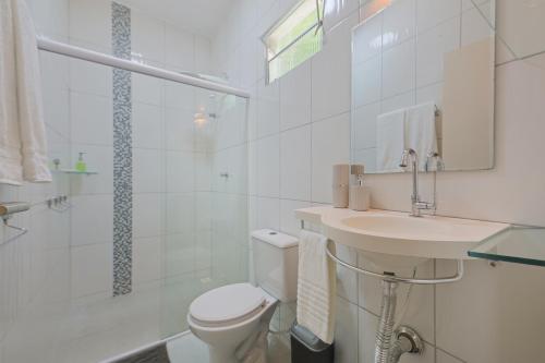 a white bathroom with a toilet and a sink at Casa Maravida in Maragogi