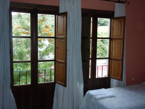 a bedroom with two large windows and a bed with a bedspread at Casa de la Fuente in Tolox