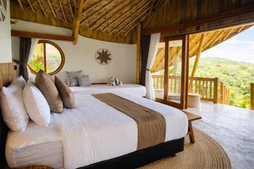a bedroom with two beds and a large window at Green Poya - Luxury Eco Bambu Resort in South Lombok in Selong Belanak