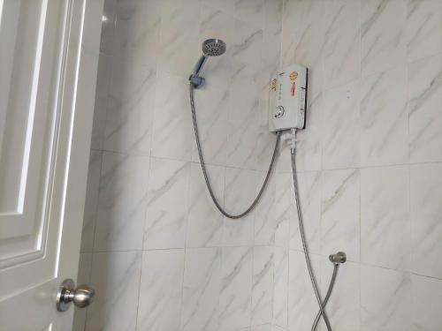a shower with a shower head on a white tile wall at Heimat Garden Homestay in Ban Lo Pa Ret