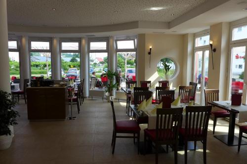 a dining room with tables and chairs and windows at Hotel & Ristorante Passarelli in Warthausen
