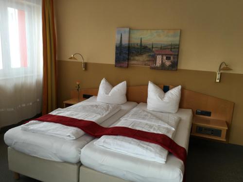 1 dormitorio con 1 cama con sábanas y almohadas blancas en Hotel & Ristorante Passarelli, en Warthausen