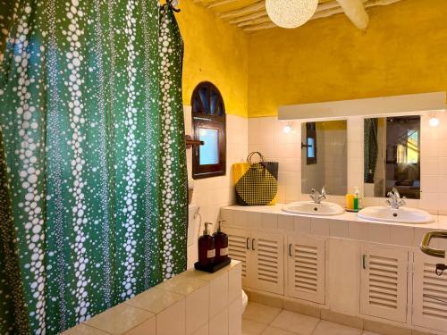 a bathroom with two sinks and a shower curtain at Casa Hera Diani in Diani Beach