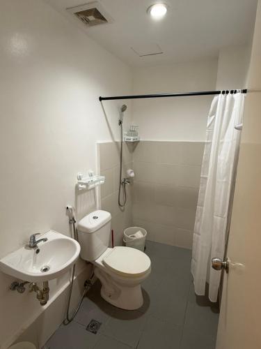 a white bathroom with a toilet and a sink at Minimalist Retreat in Minglanilla