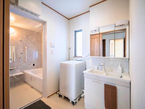a bathroom with a sink and a shower and a tub at Inamine Terrace in Nago