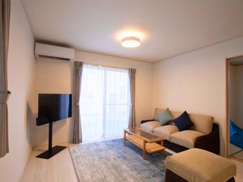 a living room with a couch and a tv at Inamine Terrace in Nago