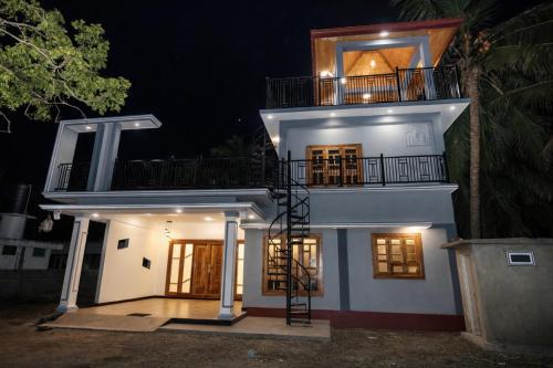 a white house with a balcony on top at night at Sai Guest House in Chavakachcheri
