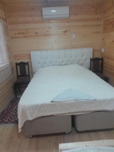 a white bed in a room with a wooden wall at Riverside Nature in Martvili