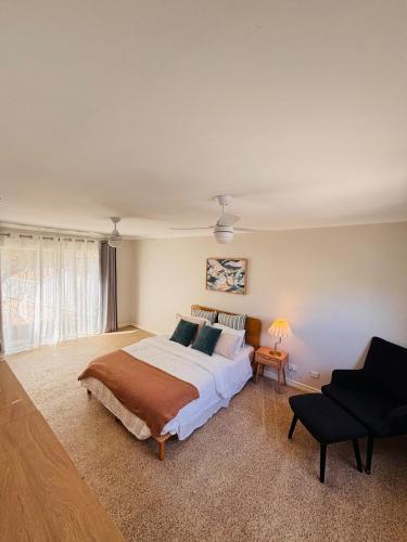 a bedroom with a large bed and a chair at Esperance Seaside Cottage in Esperance