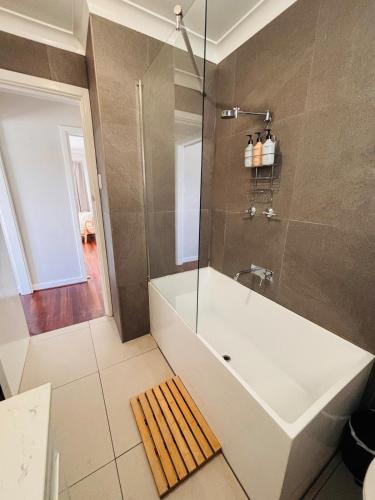 a bathroom with a tub and a glass shower at Esperance Seaside Cottage in Esperance